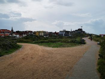 Footpath amidst buildings against sky