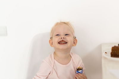 Portrait of cute girl with arms raised sitting on sofa at home