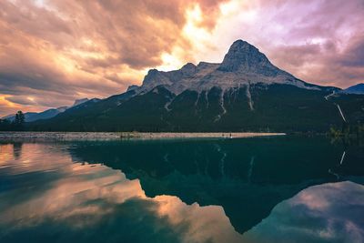 Scenic view of lake and mountains against cloudy sky during sunset