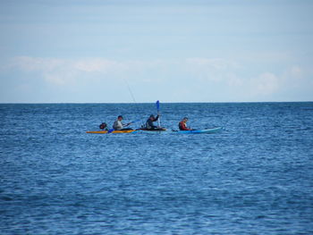 People on boat in sea against sky