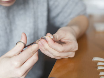 Midsection of woman cutting artificial nails