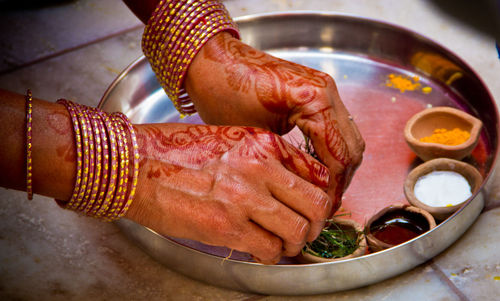 Cropped hands of woman holding herbs in plate