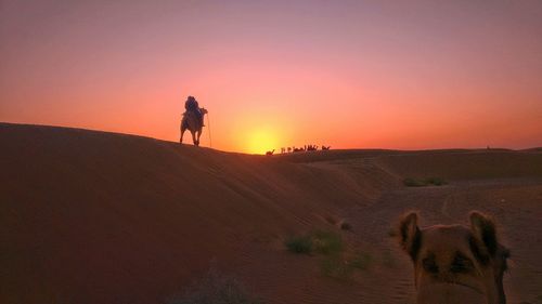 Silhouette man standing on desert against sky during sunset