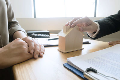 Midsection of man and woman reading book on table