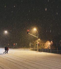People walking on illuminated street in winter at night