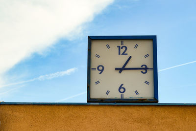 Low angle view of clock against sky