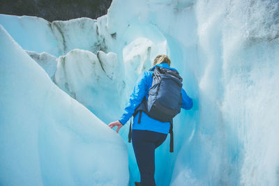 Rear view of woman walking on snowcapped mountain during winter