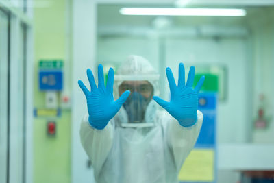 Midsection of person with arms raised standing against wall