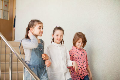 Portrait of friends standing against wall