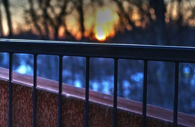 Close-up of railing against sky during sunset