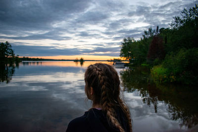 Rear view of woman looking at lake against sky