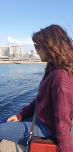 Woman sitting on shore against sky