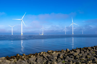 Wind turbines on sea against sky