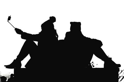 Low angle view of silhouette men against clear sky