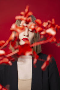 Young woman with twig against red background