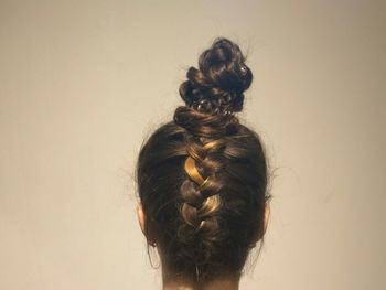 Rear view of woman with braided hair against beige background