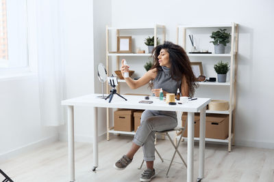 Woman filming make-up tutorial through camera at home