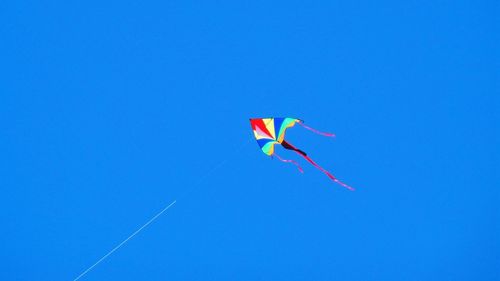 Low angle view of kite flying against clear blue sky