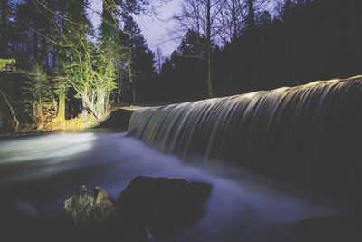 Scenic view of waterfall in forest at night