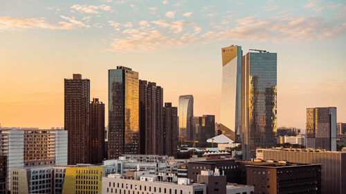 Modern buildings in city against sky during sunset