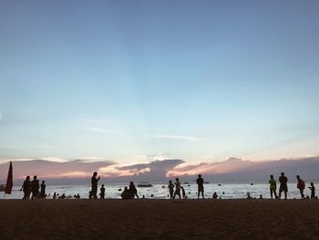 Silhouette people on beach against sky during sunset