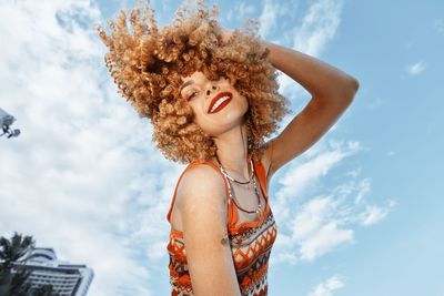 Low angle view of young woman standing against sky