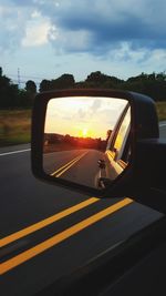 Reflection of sky on side-view mirror at sunset