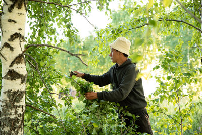 Side view of man standing by tree