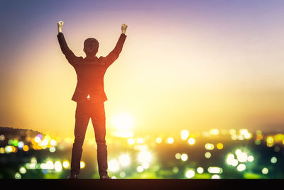 Double exposure of man standing against illuminated city at dusk