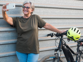 Smiling senior woman taking selfie with bicycle