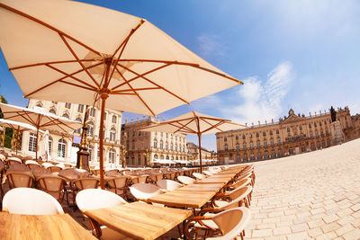 Chairs and tables in city against sky