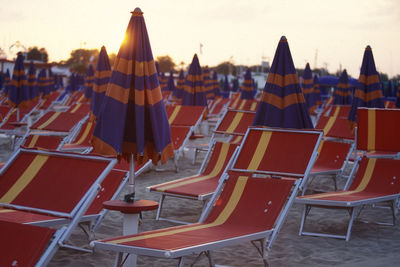 Empty chairs and tables against clear sky during sunset