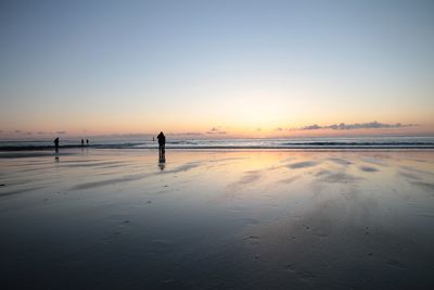 Silhouette person standing on beach against sky during sunset