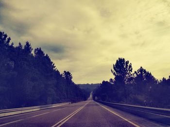 Road amidst trees against sky