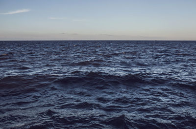 Scenic view of waves in sea against sky during sunset