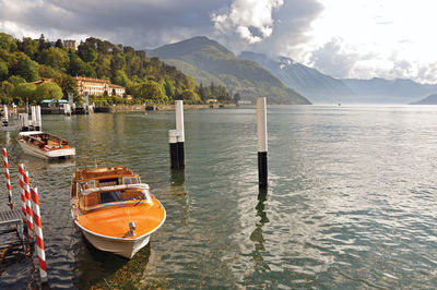 Lake como in a cloudy day with motorboat and harbor in bellagio, italy.