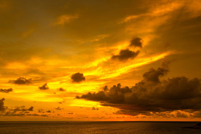 Scenic view of sea against dramatic sky during sunset