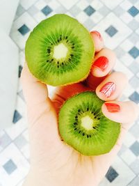 Cropped hand holding sliced kiwi at home