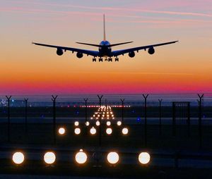 Airplane flying in sky at sunset