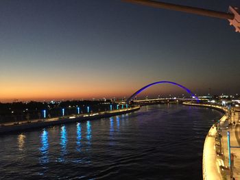 Illuminated bridge over river against sky at night