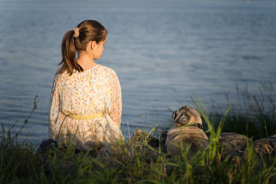 Side view of young woman standing by lake