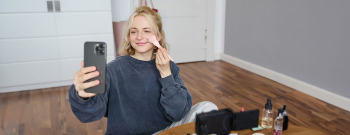 Portrait of young woman using mobile phone while sitting at home