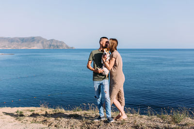 Romantic couple with dog standing against sea