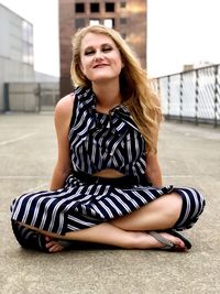 Portrait of beautiful young woman sitting in city