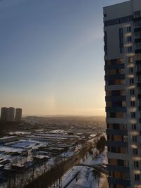 Buildings in city against clear sky during sunset