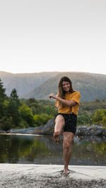 Portrait of young woman standing on mountain against sky