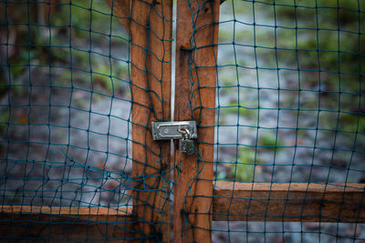 Close-up of metal gate against fence