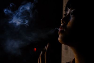 Thoughtful woman exhaling smoke at night