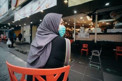 A lady in hijab waiting and practicing social distancing outside a restaurant