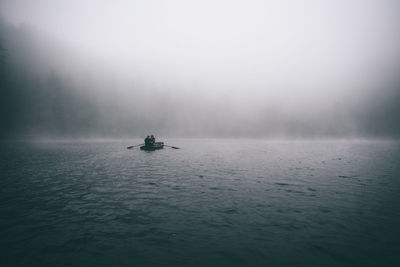 People in boat on sea against waterfall